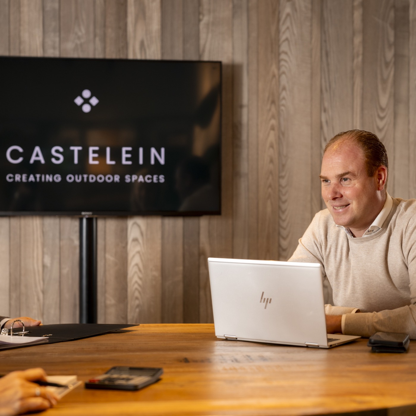 Dieter Castelein in een bespreking met een klant in de Castelein Outdoor showroom, met het bedrijfslogo op de achtergrond.