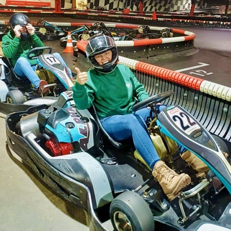Medewerkers van Castelein Outdoor tijdens een teambuildingactiviteit op een indoor kartbaan, gekleed in bedrijfsuniform.