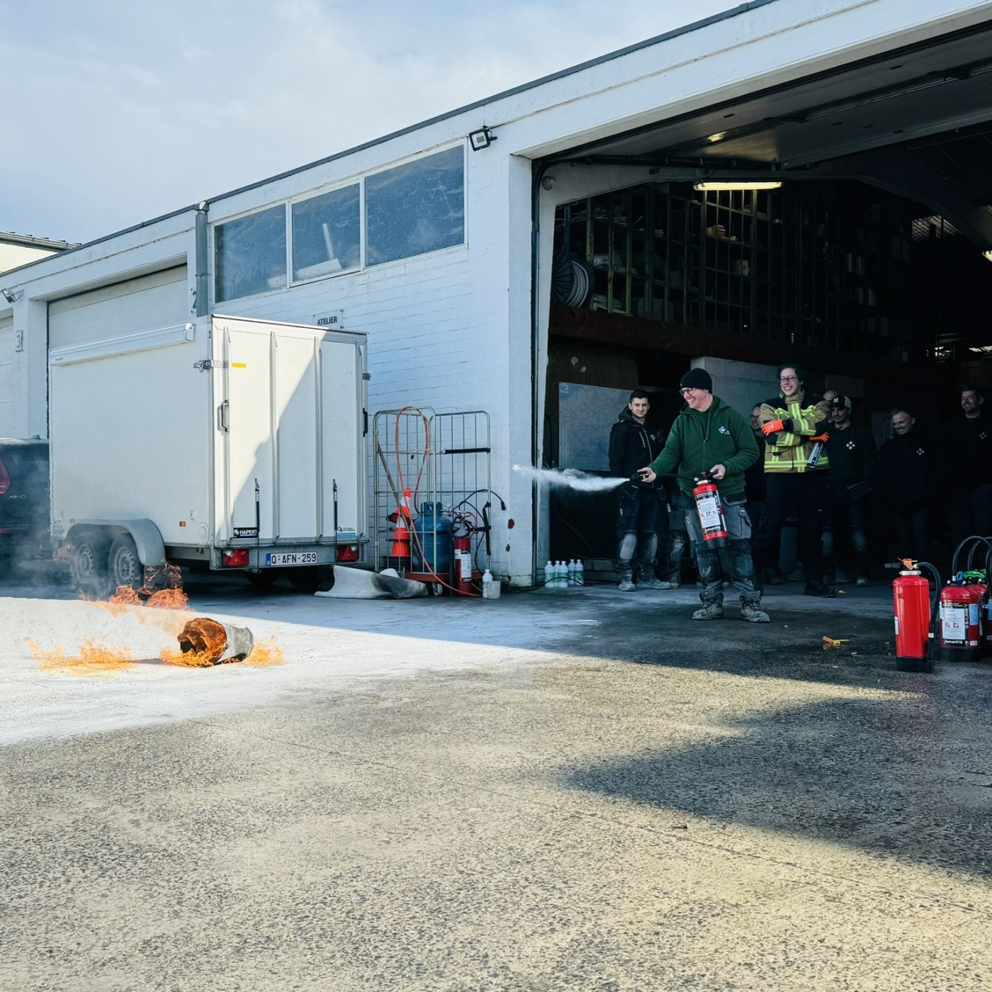 Medewerkers van Castelein Outdoor oefenen met brandblusapparaten tijdens een veiligheidstraining op het bedrijfsterrein.