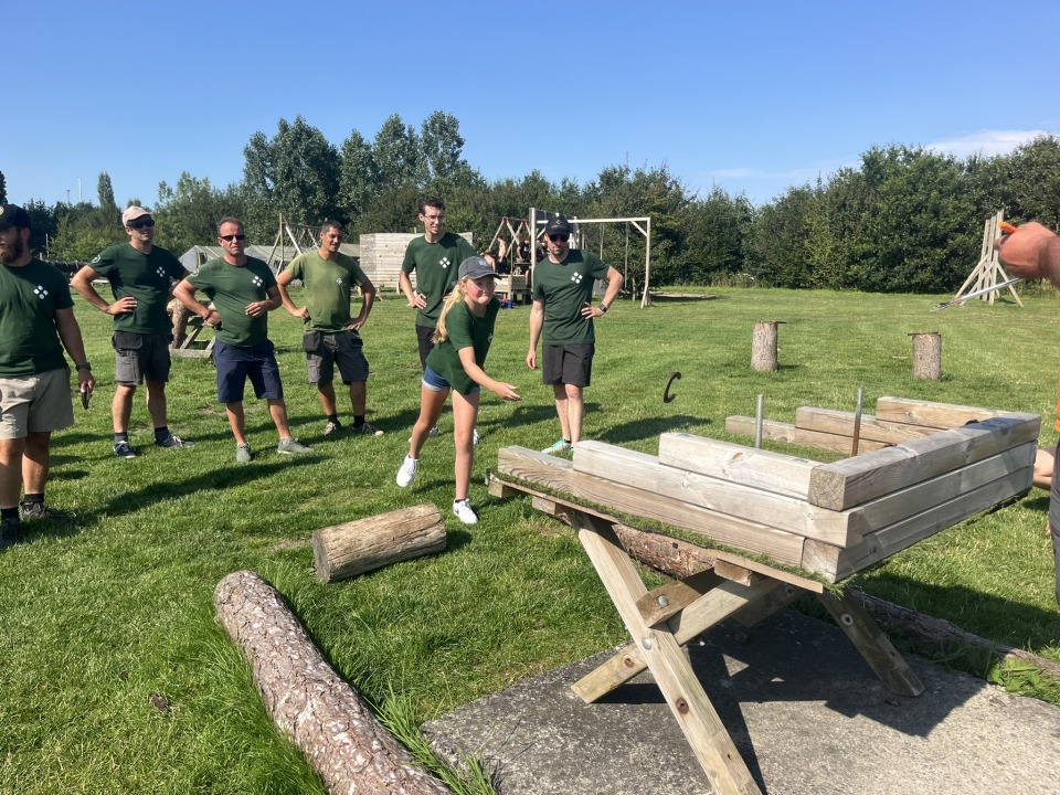 Medewerkers van Castelein Outdoor gooien hoefijzers tijdens een teambuildingwedstrijd op een grasveld.