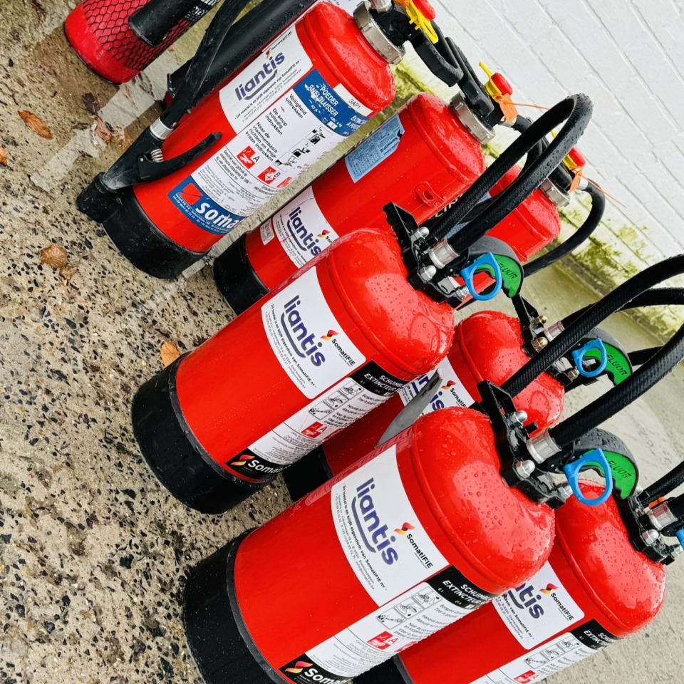 Een rij brandblussers klaar voor gebruik tijdens de Brand- en EHBO- training.