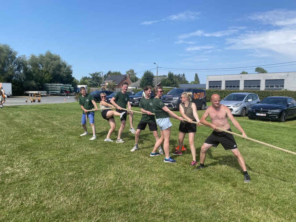 Deelnemers trekken samen aan een touw tijdens een touwtrekwedstrijd op het grasveld.