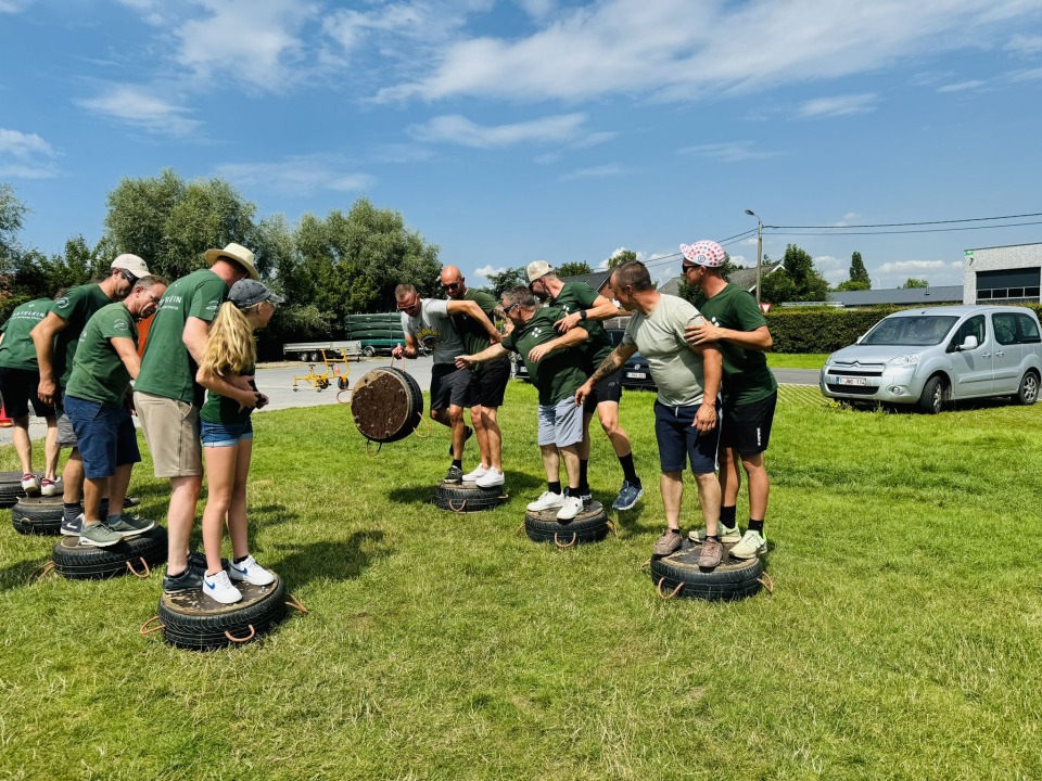 Groep collega's werkt nauw samen op banden om hun balans te vinden tijdens de teambuildingactiviteiten.