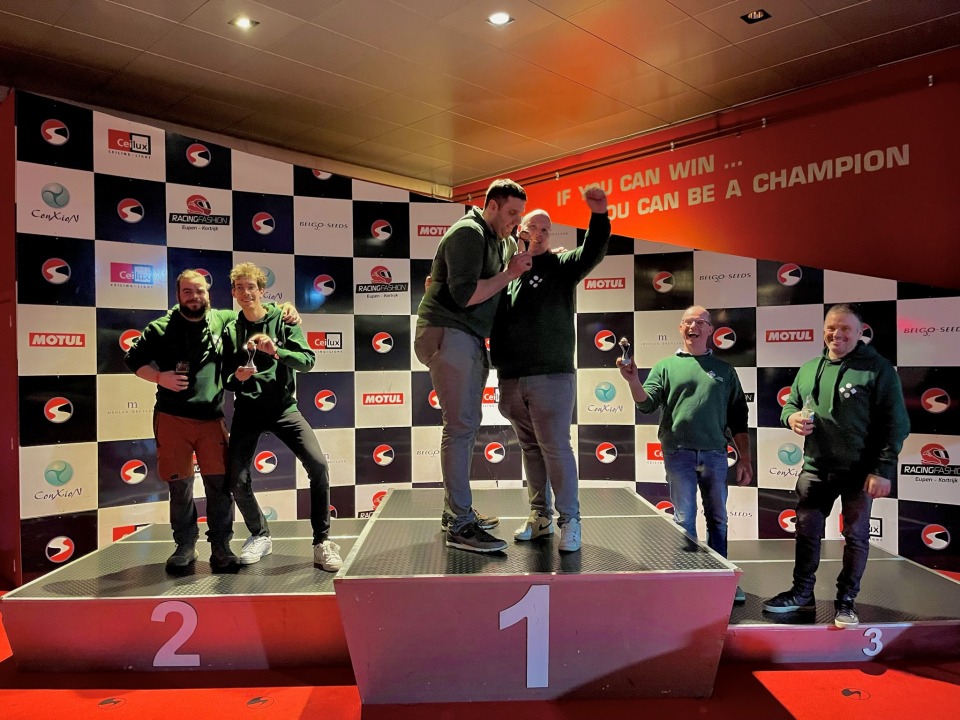 De winnaars van de kartwedstrijd staan op het podium met hun trofeeën.