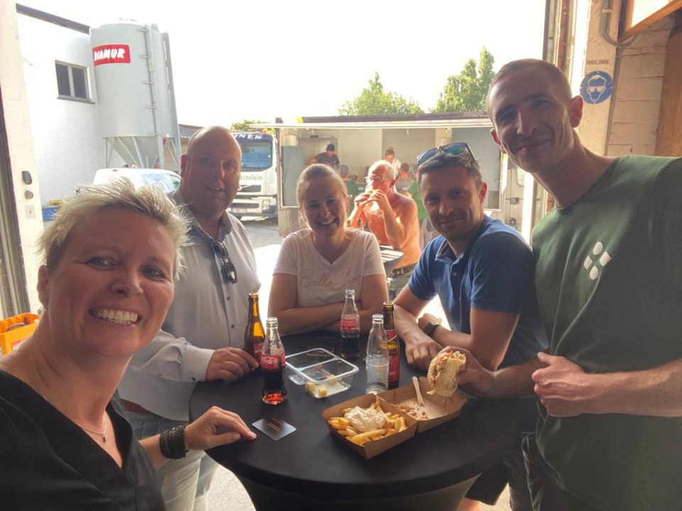 Medewerkers van Castelein Outdoor genieten van frietjes en hamburgers op de koer.